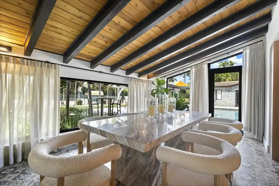 Casa Club dining room with a marble-topped table, curved cream chairs and glass doors to the pool
