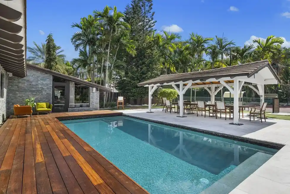 Casa Club pool with Ipe decking and a white pergola among palms