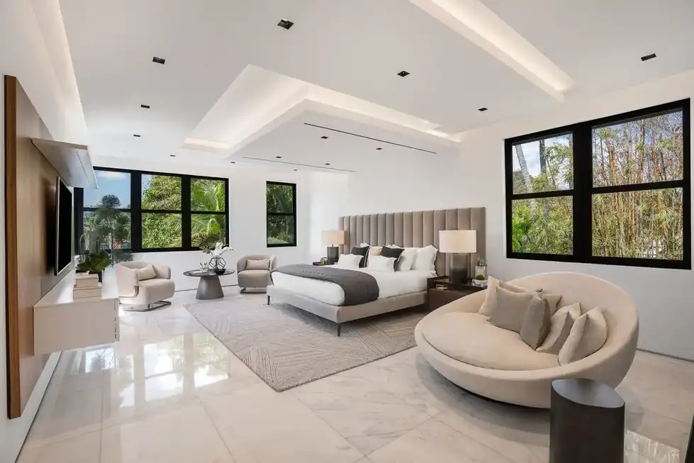 Casa Exumas master suite with a tufted headboard, a round cream lounge chair and a wood wall panel