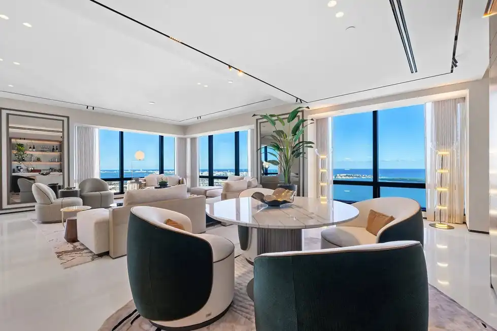 Lower PH66 living room with curved chairs and floor-to-ceiling windows over Biscayne Bay