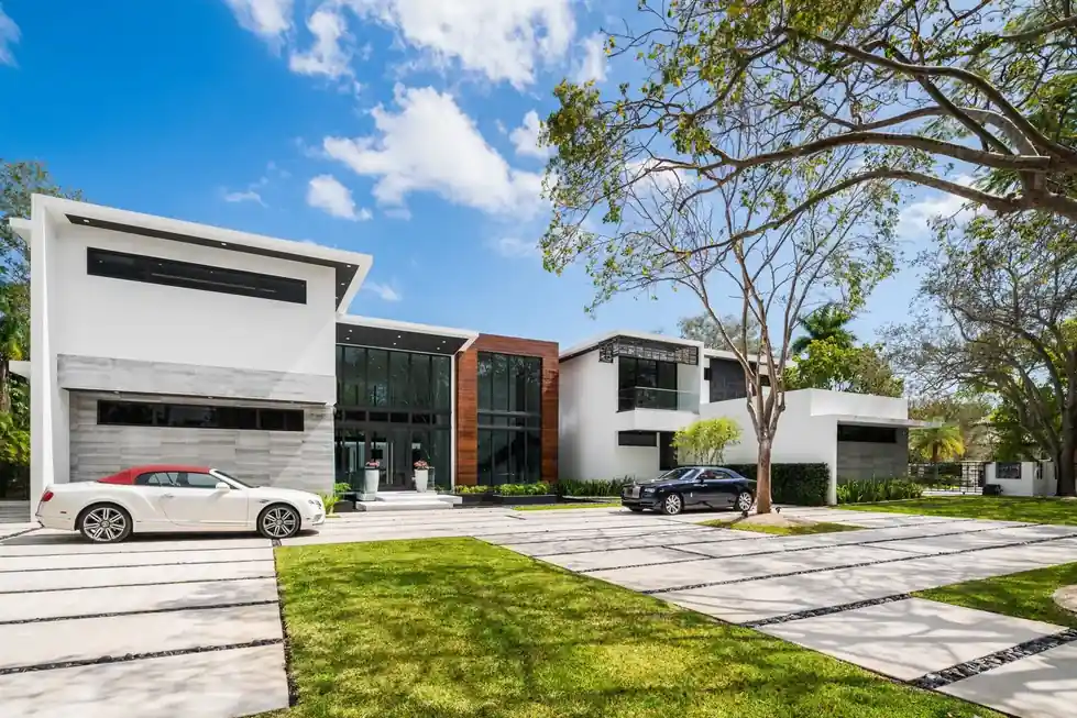 Casa Pinecrest modern facade with white stucco volumes and a gated motor court