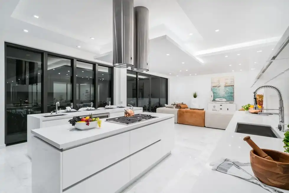Casa Pinecrest white kitchen with a long island and a steel range hood
