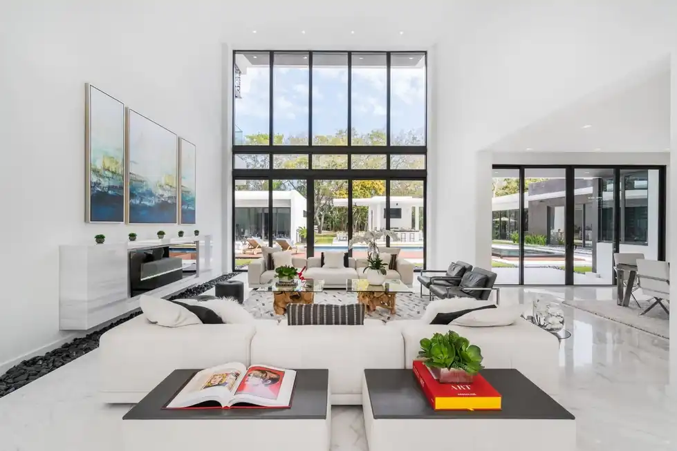 Casa Pinecrest living room with a white sectional, white marble floors and a wall of glass onto the pool
